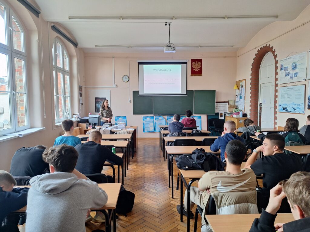 uczniowie siedzący w ławkach podczas prelekcji,.