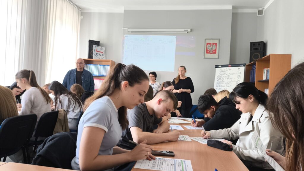 Młodzież Siedząca W ławkach Wypełnia Dokumenty Podczas Zajęć W Tle Doradcy Prowadzący Zajęcia